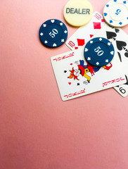 Chips and cards for poker on pink background. Gambling. Copy space.