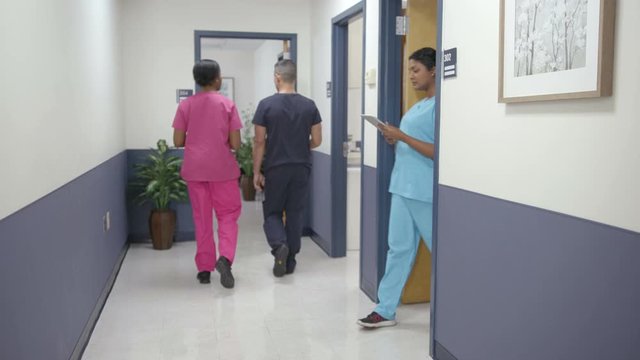 Nurses walking in hospital hallway, right to left camera move