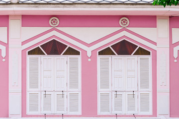 classic white and wood window at a pink concrete building.