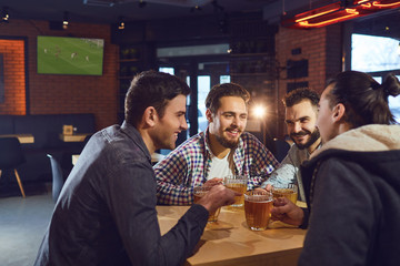Friends talk, drink beer in a bar.