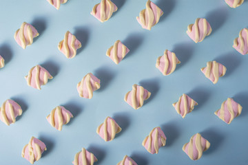 Colorful marshmallow laid out on blue paper background. pastel creative textured pattern. minimal