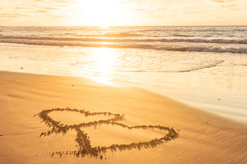 Valentines day on sunny beach. Two hearts drawn in sand, love concept