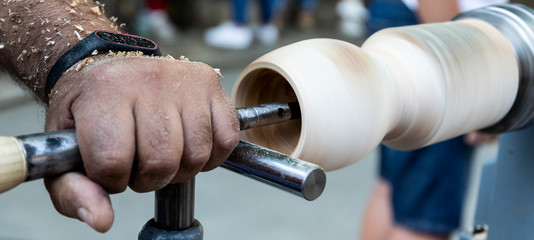 A craftsman carves a piece of wood with a lathe.