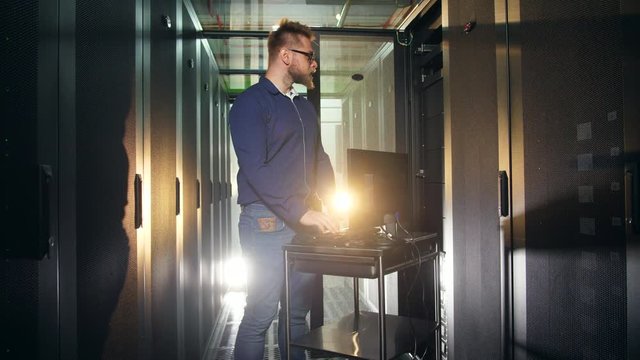 Support technician is analyzing servers on his computer. IT programer working in Data Center.