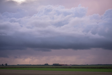Stormclouds and falling rain at sunset