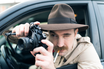 Obraz premium Paparazzo using vintage camera in his car