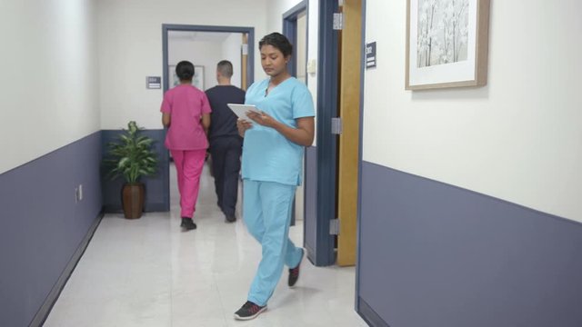 Nurses walking in hospital hallway, left to right camera move