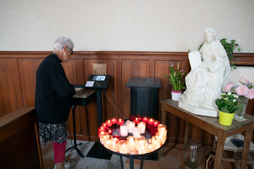 A woman in a church uses a credit card payment terminal to buy candles or make a donation. It says...