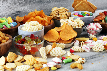 Salty snacks. Pretzels, chips, crackers and candy sweets on table