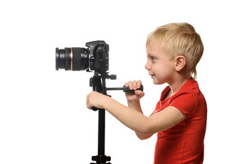 Blond boy shoots video on DSLR camera. Side view. White background, isolate