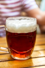 Man is holding a freshly tapped glass of beer in his hand