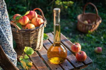 A bottle of apple cider vinegar with ripe apples