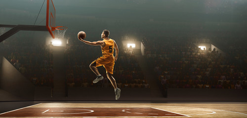 Basketball player on sports arena in action with the ball. Slam dunk