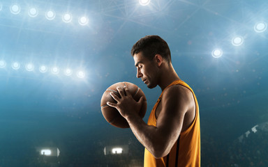 Professional basketball player on floodlit basketball arena with the ball