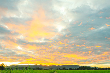 The beautiful landscape at sunrise over rice fields and hills, the beauty of the golden sunlight hits the rain clouds,  landscape in Chiang Rai, Thailand.
