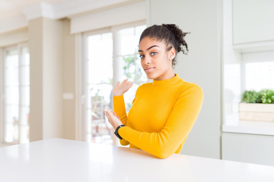 Beautiful african american woman with afro hair wearing a casual yellow sweater Inviting to enter smiling natural with open hand