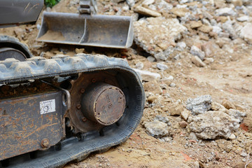 Rubber track of a digger against concrete and earth debris