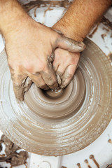 View at an artist makes clay pottery on a spin wheel