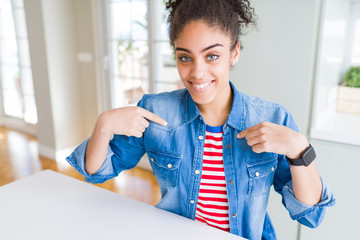 Beautiful young african american woman with afro hair wearing casual denim jacket looking confident...