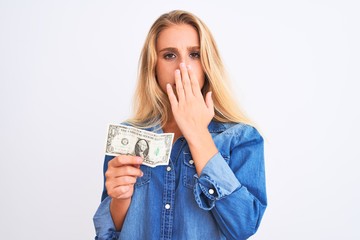 Young beautiful blond woman holding dollar standing over isolated white background cover mouth with...