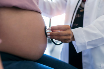 Woman gynecologist checking the heartbeat baby of her pregnant patient in the clinic.