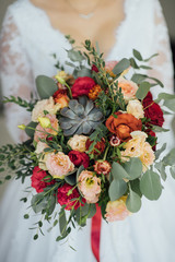 bride in a white dress holding a bouquet of flowers and greenery