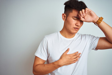 Fototapeta premium Young asian chinese man wearing t-shirt standing over isolated white background Touching forehead for illness and fever, flu and cold, virus sick