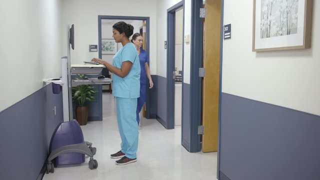 Hospital hallway, nurses pass nurse  on EMR cart camera moves left right