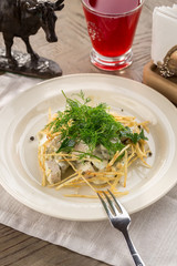 Chicken salad with potatoes and mayonnaise and glass of red drink on wooden table