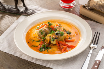 Cabbage stuffed rolls with meat, rice and vegetables on white plate on wooden table