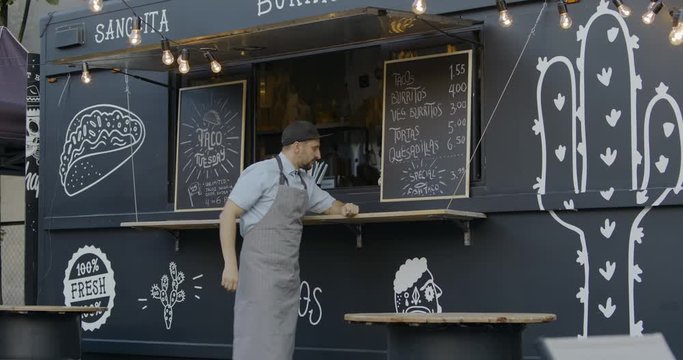 WIDE Happy smiling middle-aged small business owner posing near his Mexican food truck. 4K UHD RAW graded footage