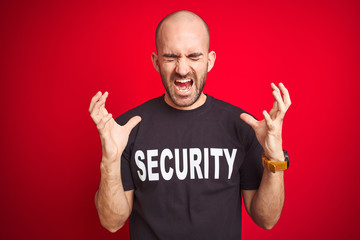 Young safeguard man wearing security uniform over red isolated background celebrating mad and crazy for success with arms raised and closed eyes screaming excited. Winner concept