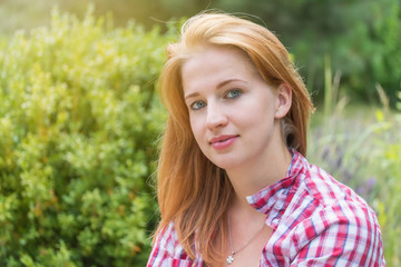 Naklejka premium Attractive young woman is posing and looking at the camera at the garden. 