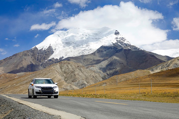 LOW ANGLE: White car drives down the road leading past a glacier in Himalaya.