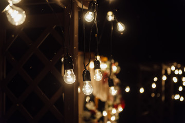 night wedding ceremony. A garland of light bulbs. candles in glass flasks in the evening.