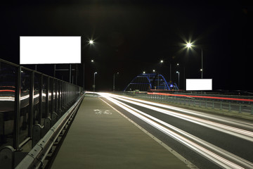 Światła samochodów w nocy na autostradzie, bilbord reklamowy.
