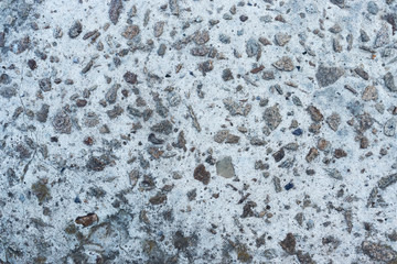 Background in the form of a concrete surface of gray color with interspersed small stones and a characteristic structure