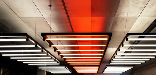 Ceiling with hanging down neon tubes. Lighting for halls, offices and large buildings