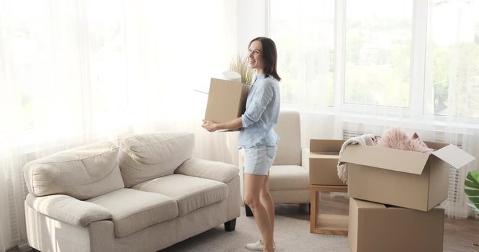 Excited woman moving into new house with carton box and celebrating success