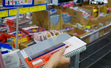 Student girl comparing school products in stationery shop. Back to school concept photo in a hypermarket. Beginning of the new training / education season. Blurred background.