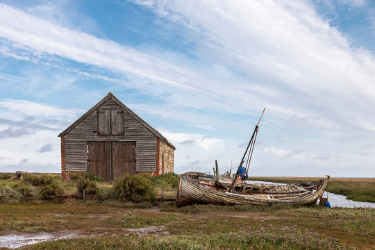 Days Gone By / An image of an old coal barn and fishing boat on a waterway illustrating days gone by at Thornham Norfolk, England, UK.