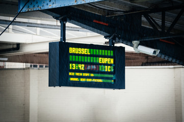 Rain water drops in front of defocused arrival departure board in Belgium Ostend train station with destination Brussels Eupen