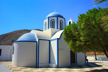 Piękny biało-niebieski kościół na tle wzgórz, Santorini, Grecja - obrazy, fototapety, plakaty