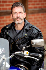 sexy biker dressed in black leather sitting on his bike