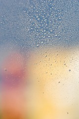 Raindrops on window glass. Gray, pink, yellow background, copy space