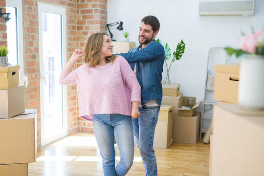 Young couple dancing celebrating moving to new apartment around cardboard boxes