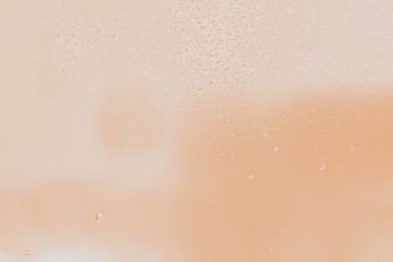 Raindrops on window glass. Peach color gradient background