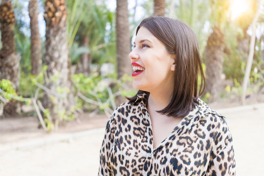 Young beautiful woman with red lips smiling happy at garden
