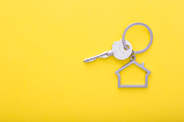 House keys with trinket on color background, top view with copy space.