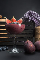 Gourmet dessert on a dark background, place for text. Berry pudding with blueberries and slices of figs. Blurred background